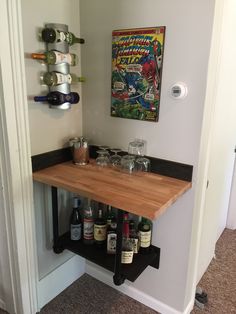 there is a shelf with bottles and glasses on it in the corner of this room