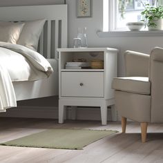 a bedroom with a bed, chair and nightstand next to a white rug on the floor