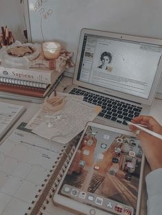 a person sitting at a desk with an ipad and books in front of them, holding a pencil