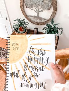 a person holding up a notebook with the words, let the morning begin and end