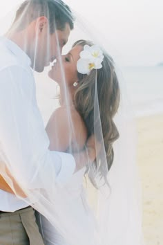 a man and woman standing next to each other under a veil