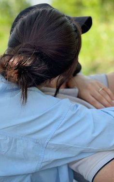 the back of a woman's head with her hands on her shoulder