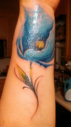 a woman's arm with a blue flower tattoo on her left wrist and yellow flowers on the other side