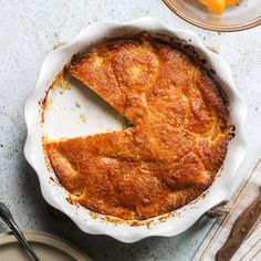 a pie sitting on top of a white plate next to utensils and an orange slice