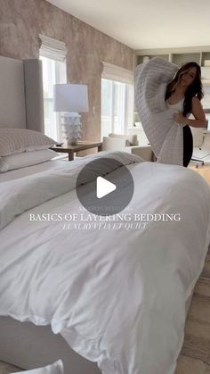 a woman standing in front of a bed with white sheets