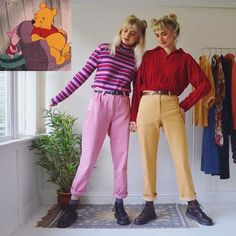 two women standing next to each other in front of a wall with winnie the pooh on it