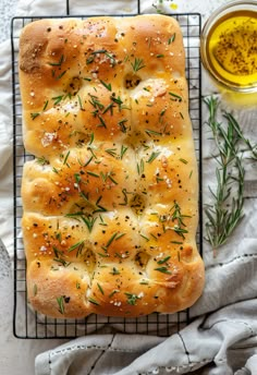 a loaf of garlic bread on a cooling rack next to a cup of olive oil