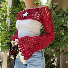 a woman wearing a red crocheted shawl with a white star on it