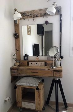 a wooden desk with a mirror and lights on top of it in front of a white wall