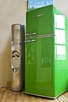 a green refrigerator sitting next to a trash can on top of a hard wood floor