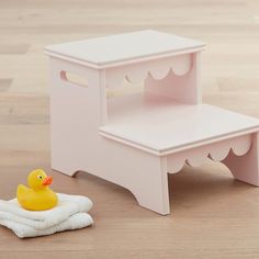 a small wooden step stool next to a rubber ducky toy