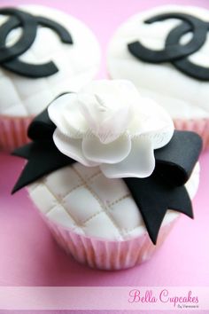 three cupcakes decorated with black and white icing on a pink tablecloth