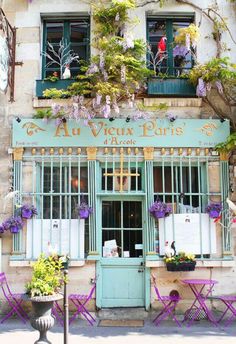 an image of a store front with flowers on the window sill and shutters