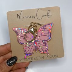 a pink butterfly shaped keychain on a card