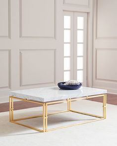 a coffee table with a bowl on top in front of a white wall and door