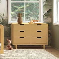 a baby crib next to a dresser with a teddy bear on it in front of a window