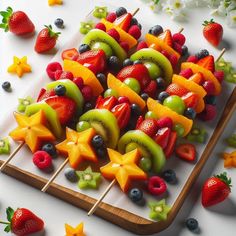 fruit kabobs arranged on a cutting board with strawberries, kiwis and blueberries