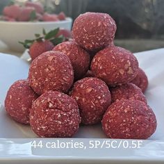 a pile of food sitting on top of a white plate next to a bowl of strawberries