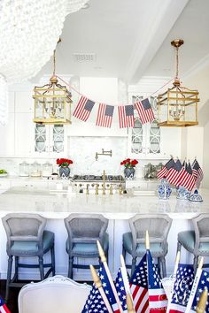 a kitchen with american flags hanging from the ceiling and chairs in front of an island