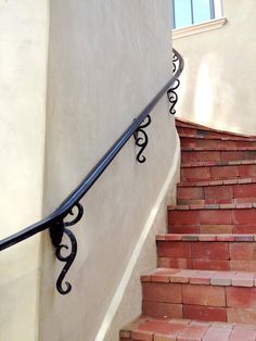 an iron handrail on the side of a building with red brick steps and railings