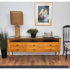 an old dresser with a painting on the wall behind it