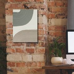 a computer monitor sitting on top of a wooden desk next to a brick wall and potted plants