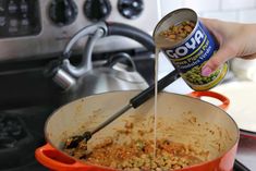 a person is pouring some food into a pot on the stove with it's lid open