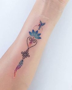 a woman's wrist tattoo with flowers and birds on the back of her arm