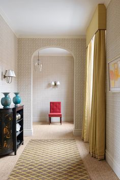 a room with a red chair in the corner and a yellow rug on the floor