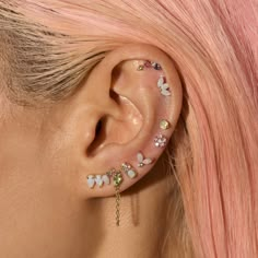 a woman with pink hair has some piercings on her ear