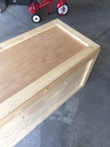 a wooden box sitting on top of a floor next to a red fire hydrant