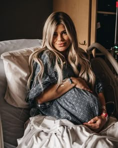 a pregnant woman sitting in a hospital bed with her stomach wrapped around her belly and looking at the camera