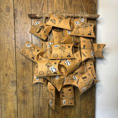 a bunch of brown paper bags hanging on a wooden wall with numbers and symbols attached to them