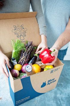 a person holding a box full of vegetables