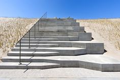 concrete steps leading up to the top of a hill with sand dunes in the background