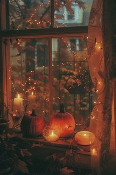 two pumpkins sitting on top of a window sill with candles in front of them