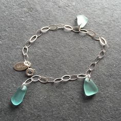 a silver bracelet with sea glass charms