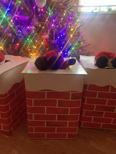 two boxes with stuffed animals on top of them in front of a christmas tree and lights