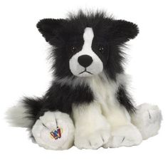 a black and white dog stuffed animal sitting on the ground with its paw up to it's face