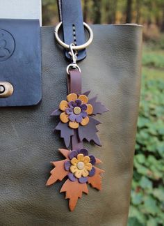 a handbag is decorated with flowers and leather handles, along with a keychain