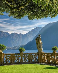 a statue is sitting on the edge of a balcony overlooking water and mountains in the distance