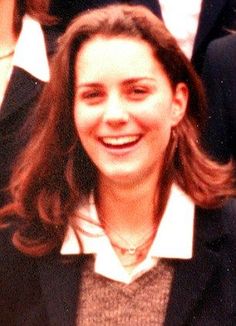 a young woman is smiling and wearing a black blazer with white collared shirt