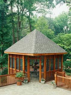 a wooden gazebo surrounded by greenery and trees