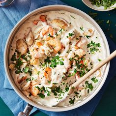 a bowl filled with shrimp, potatoes and cream sauce on top of a blue napkin