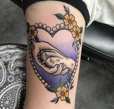 a woman's arm with a heart shaped frame and flowers on it that has an image of a man holding a baby