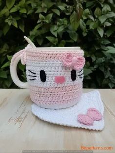 a crocheted coffee cup with a hello kitty face on it and a pink bow