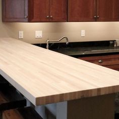 a kitchen counter top with wooden cabinets in the back ground and a sink below it