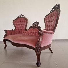 an old fashioned pink couch sitting on top of a tile floor