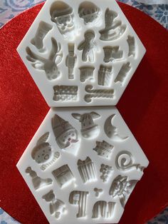 two plastic molds sitting on top of a red plate with white designs and symbols