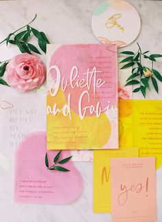 the wedding stationery is laid out on top of the marble table with pink flowers and greenery